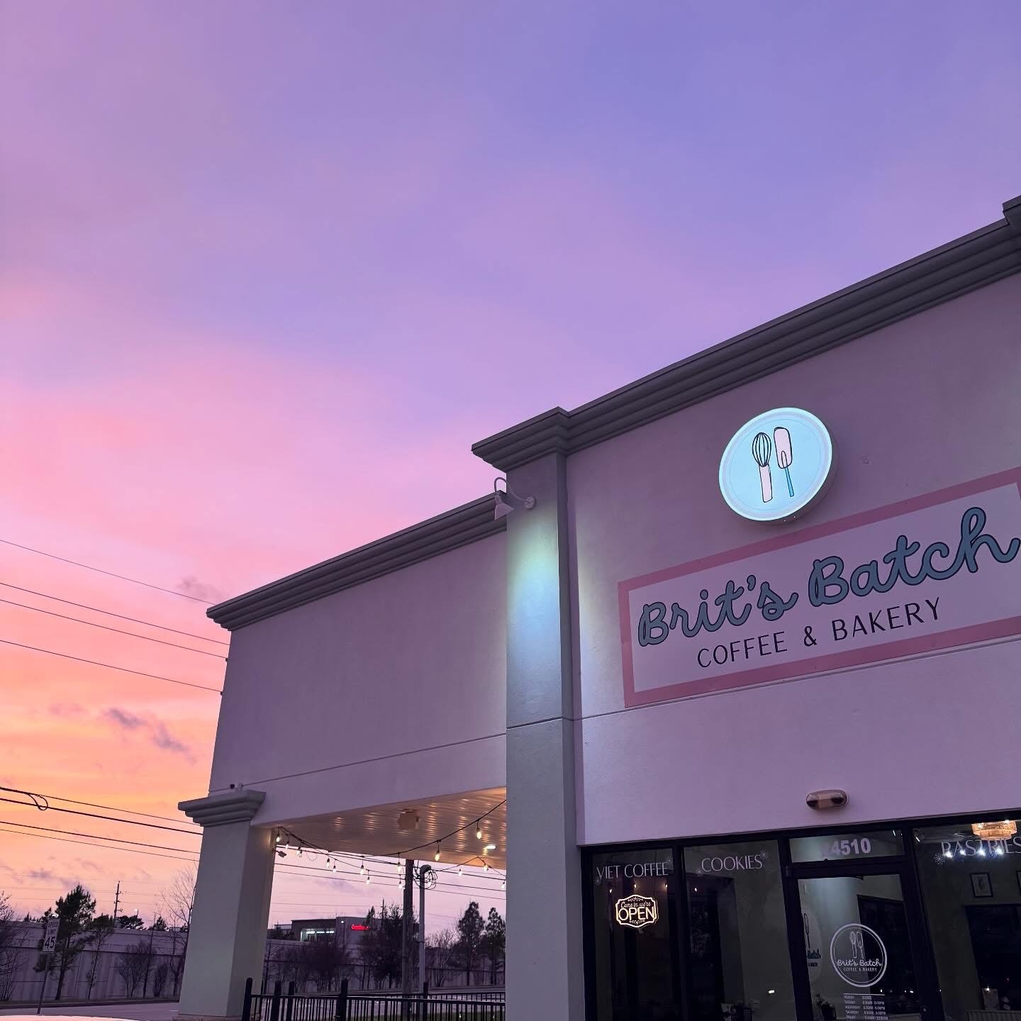 Building with a sign for Britt's Batch Coffee & Bakery against a pink and purple sky.