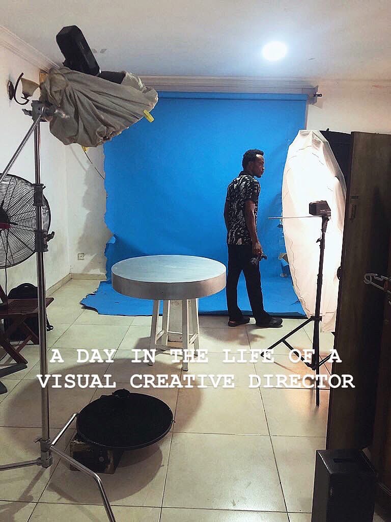 Person standing in front of a blue backdrop in a photography studio, with equipment and lighting around.