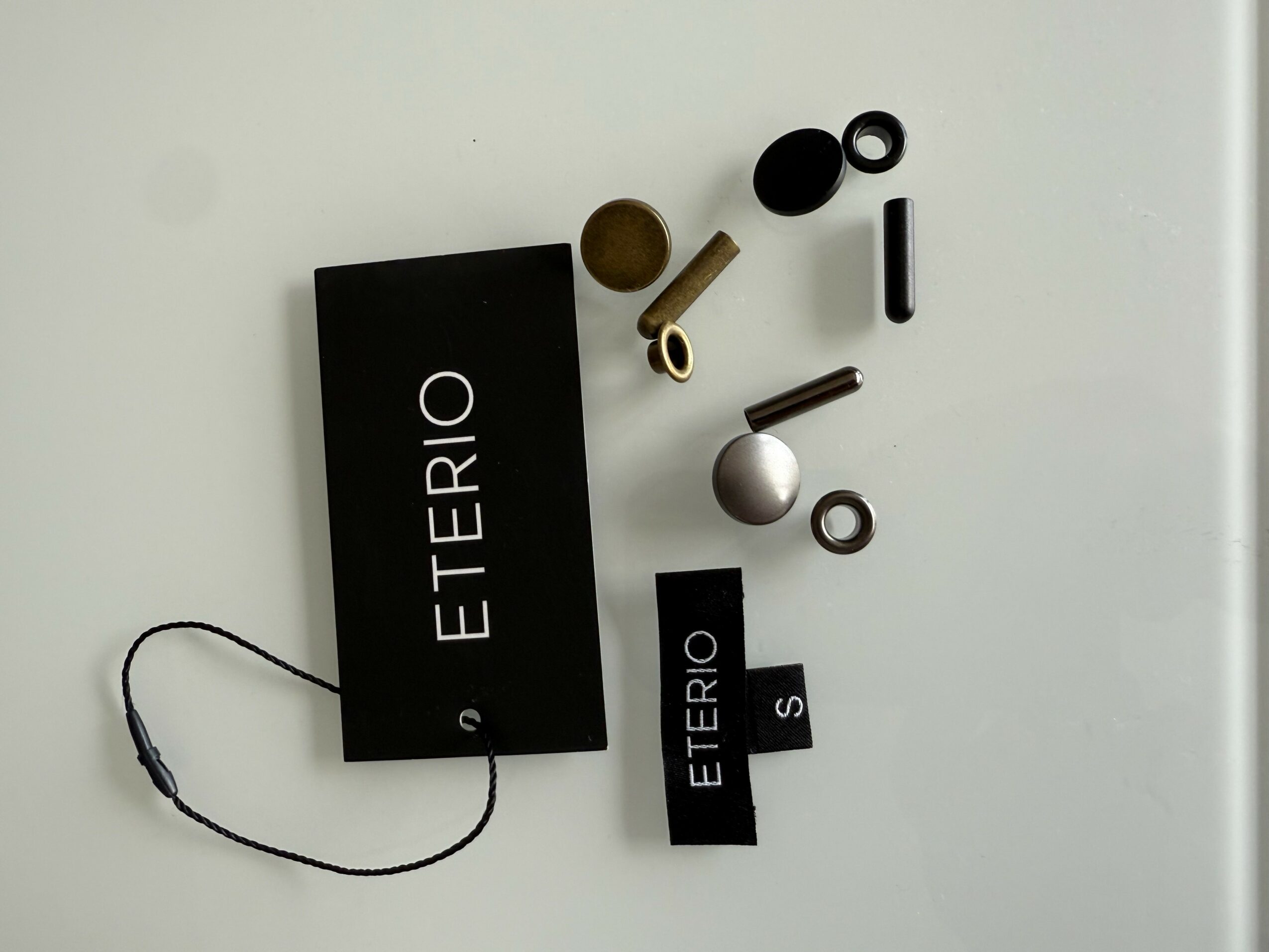 Various small objects and two black tags with white text on a white surface.