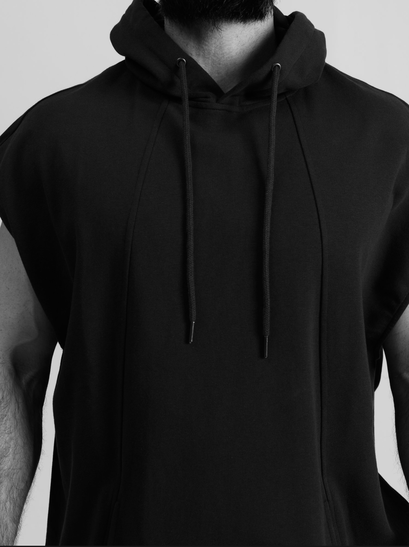 Close-up of a person wearing a black hoodie with drawstrings, focusing on the upper torso and neck area.
