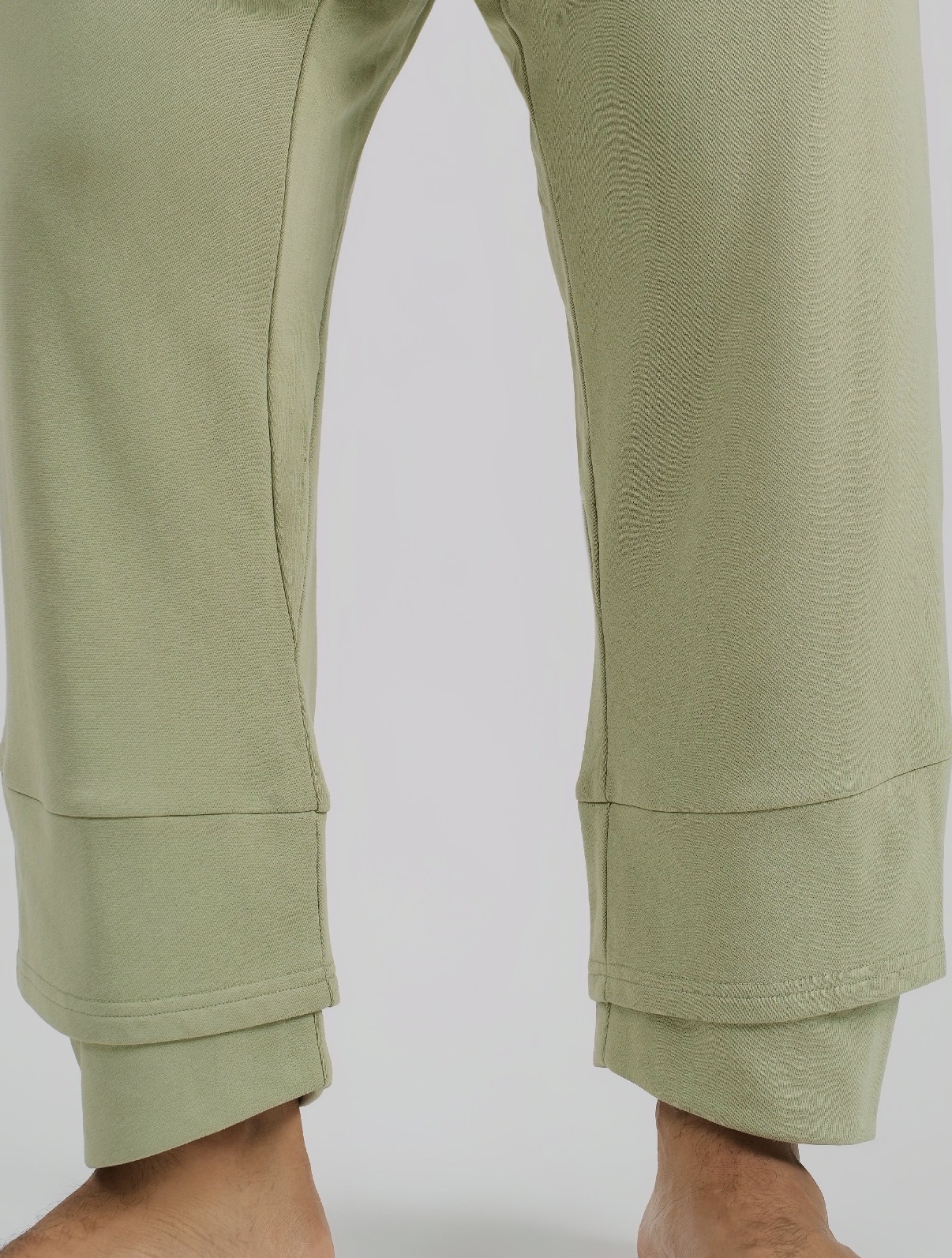Close-up of light green pants with wide cuffs, showing the lower legs and ankles.