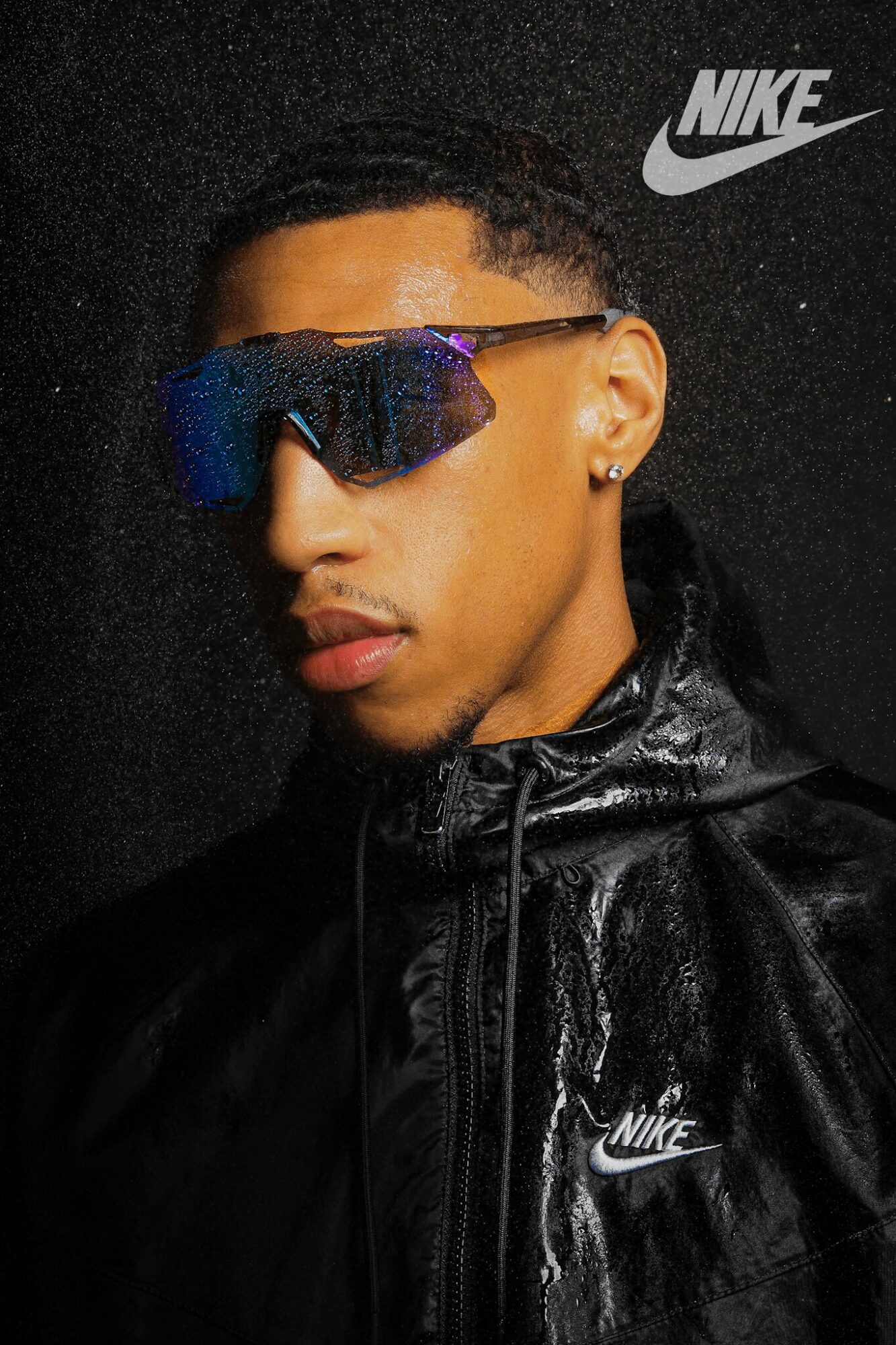 Young man wearing sunglasses and Nike jacket, with Nike logo in top right corner.
