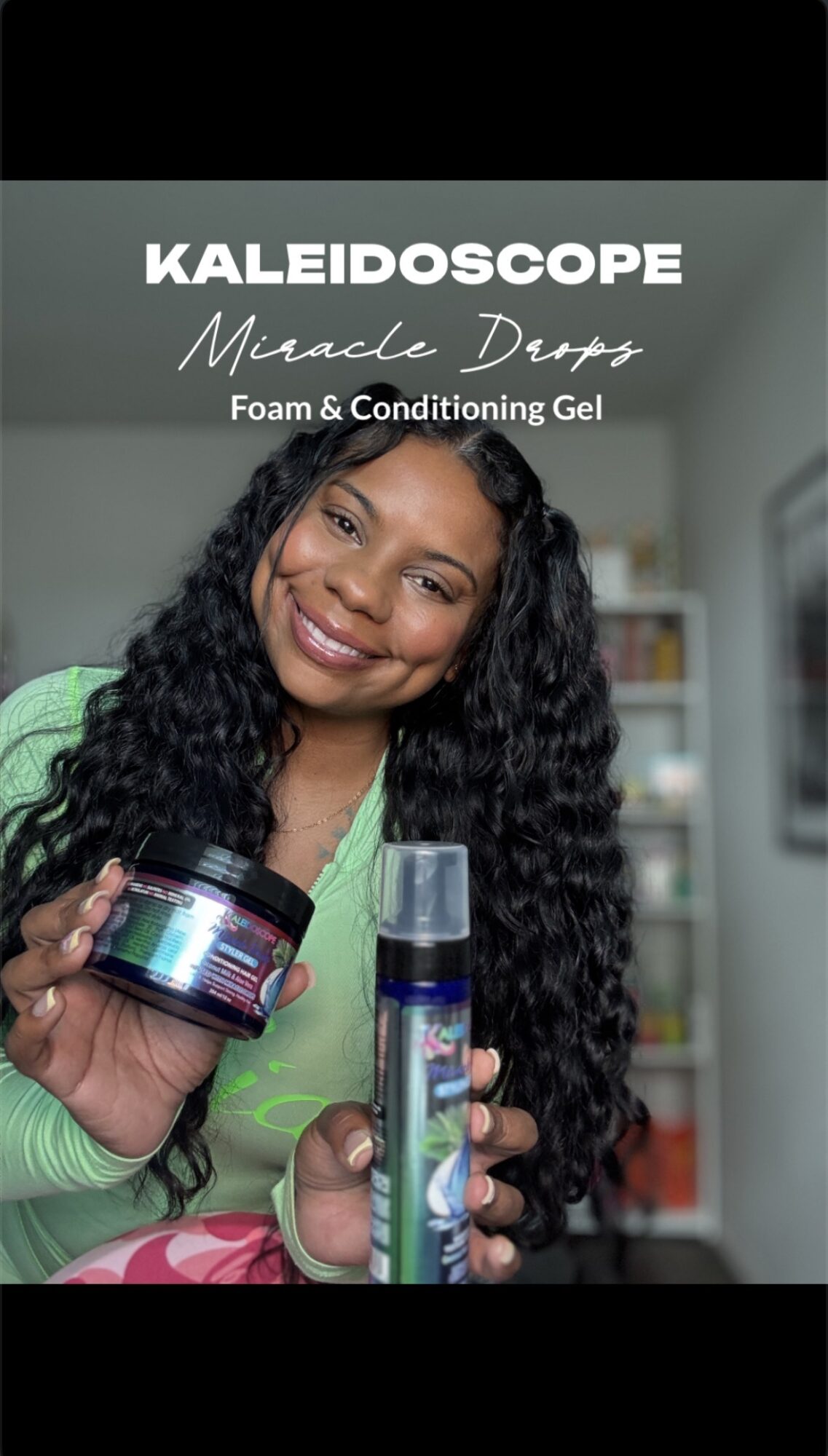 Woman smiling holding skincare products in a room with shelves, wearing a green top.