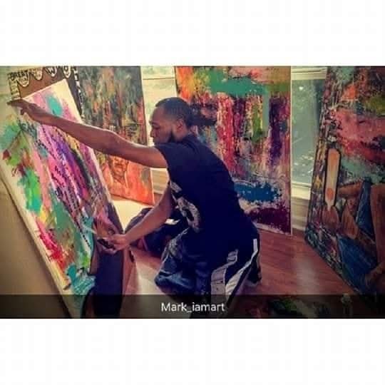 Person reaching out to touch colorful abstract paintings in an art gallery.