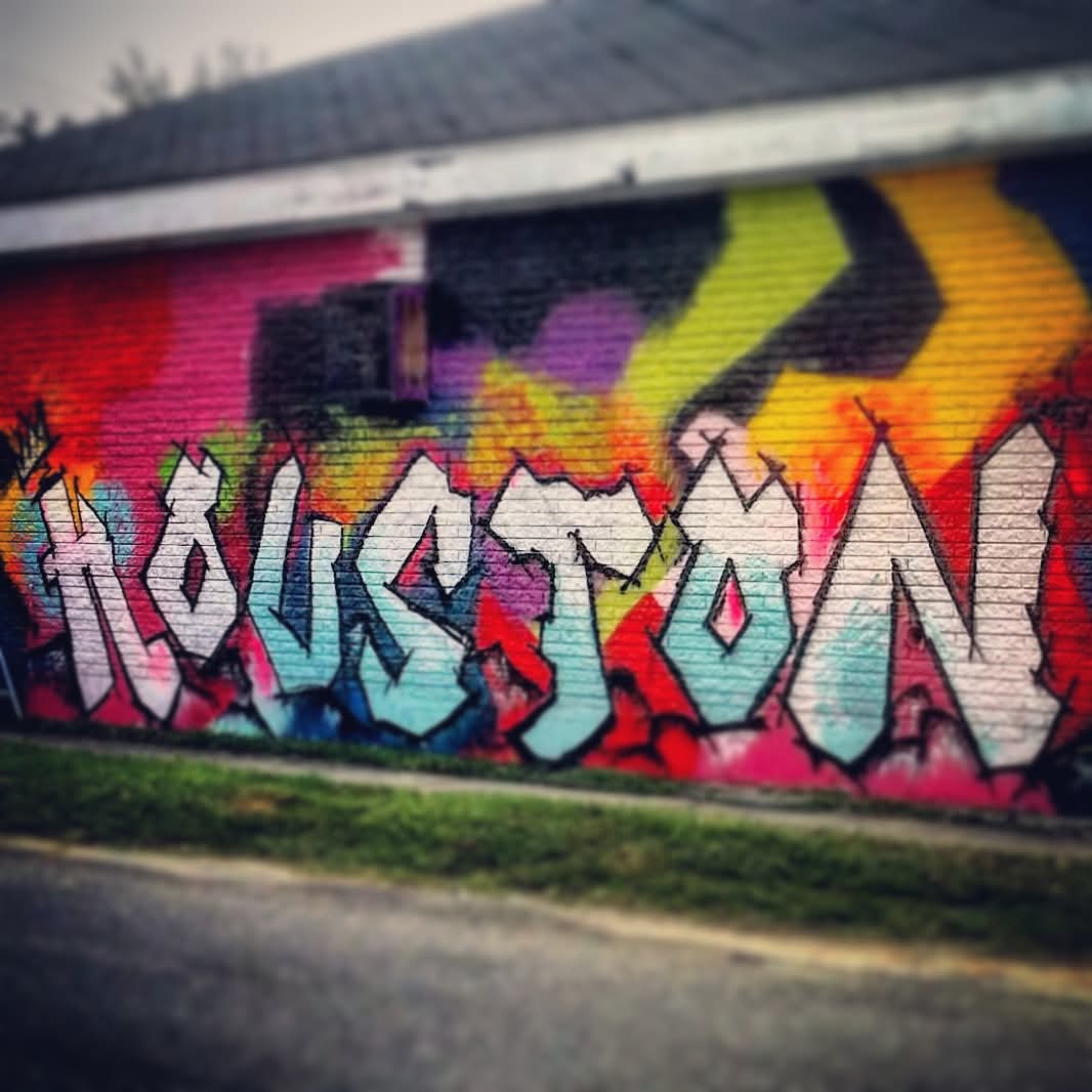 Colorful graffiti on a brick wall with various shapes and letters, vibrant background with multiple colors, street scene, sidewalk.