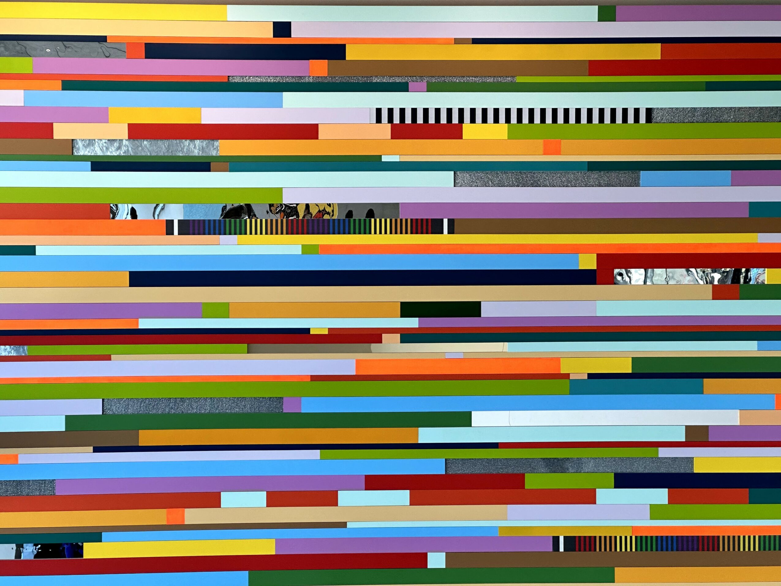 Colorful horizontal lines with some visible objects and structures in the background, creating an abstract pattern.