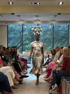 Person dressed as a rabbit walking through a room with seated people and large windows showing trees outside.