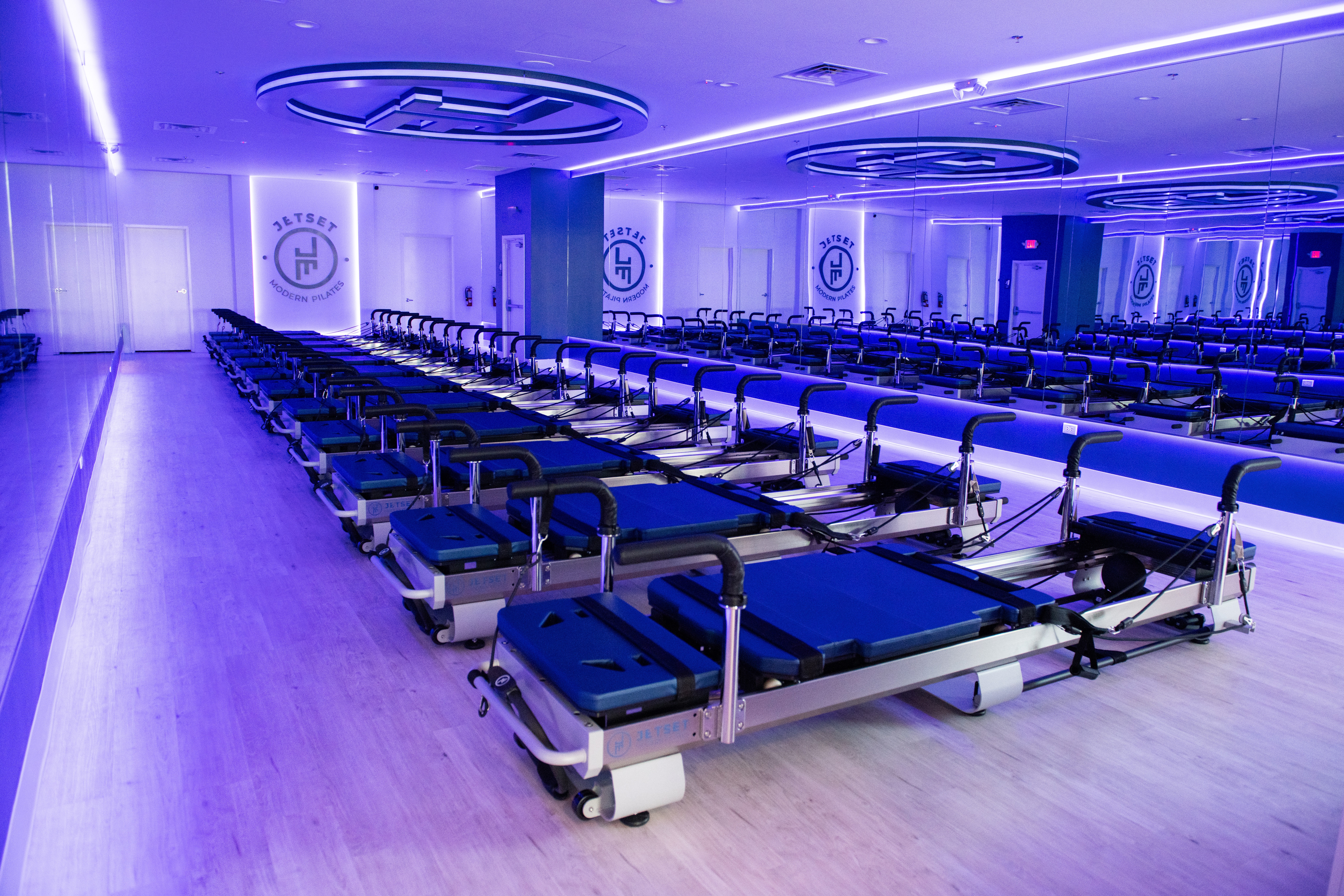 Hospital beds arranged in rows in a brightly lit, modern room with blue lighting and circular ceiling features.