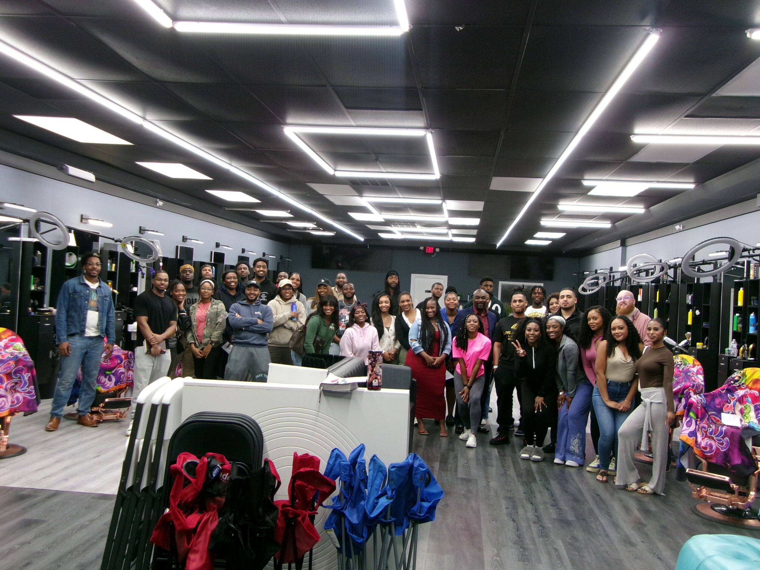 Group of people standing in a gym with exercise equipment and bright ceiling lights.