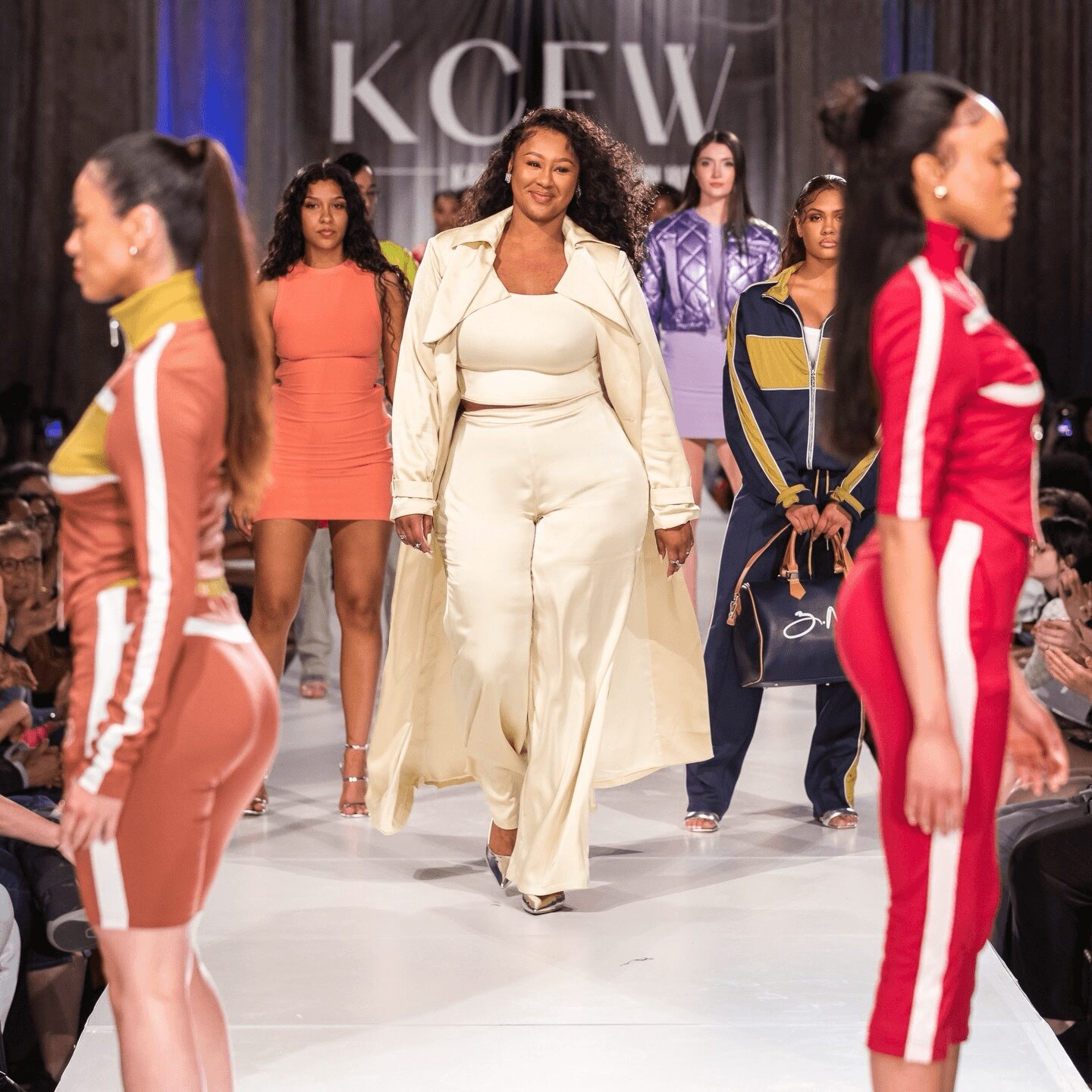 Group of diverse women walking on runway during fashion show, with