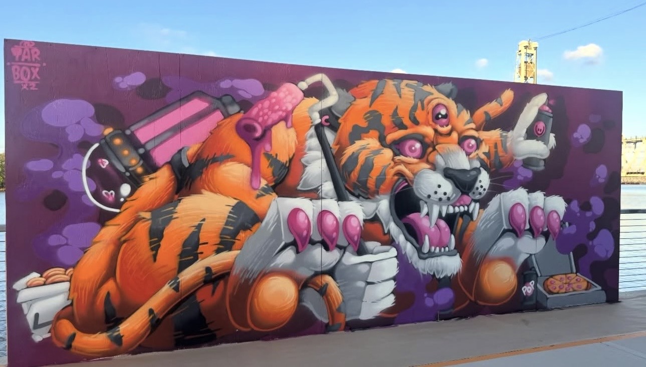 Colorful mural of a tiger with pink sunglasses, surrounded by purple clouds, on a purple background.