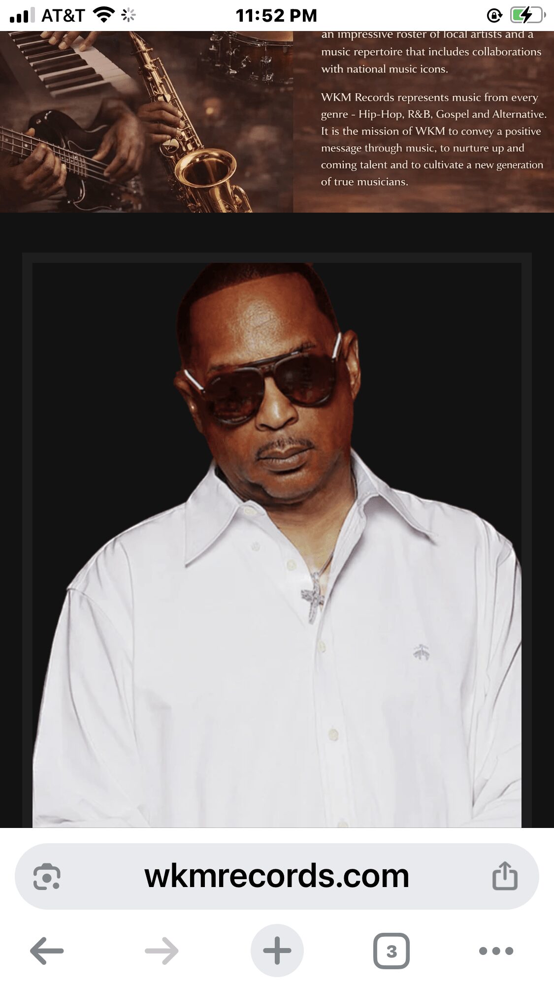 Man wearing sunglasses and a white shirt, looking at the camera, against a black background.
