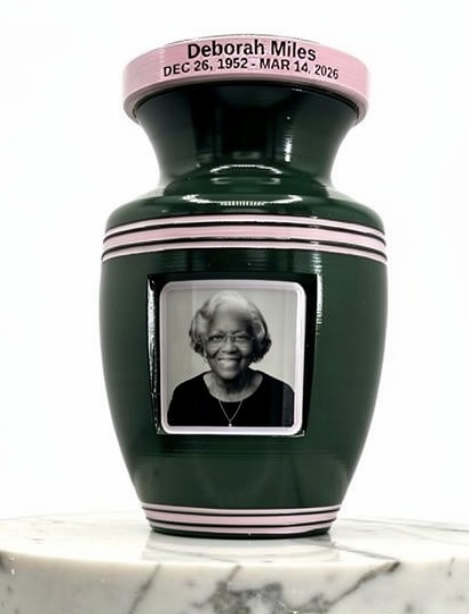 Vase with a black-and-white photo of a smiling woman, pink band with text, on a marble surface.