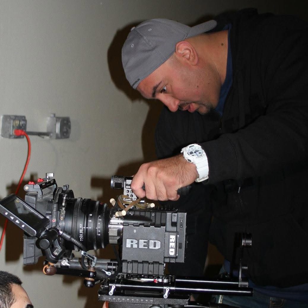 Person wearing a gray cap and black jacket working with camera equipment on a wall-mounted rig.