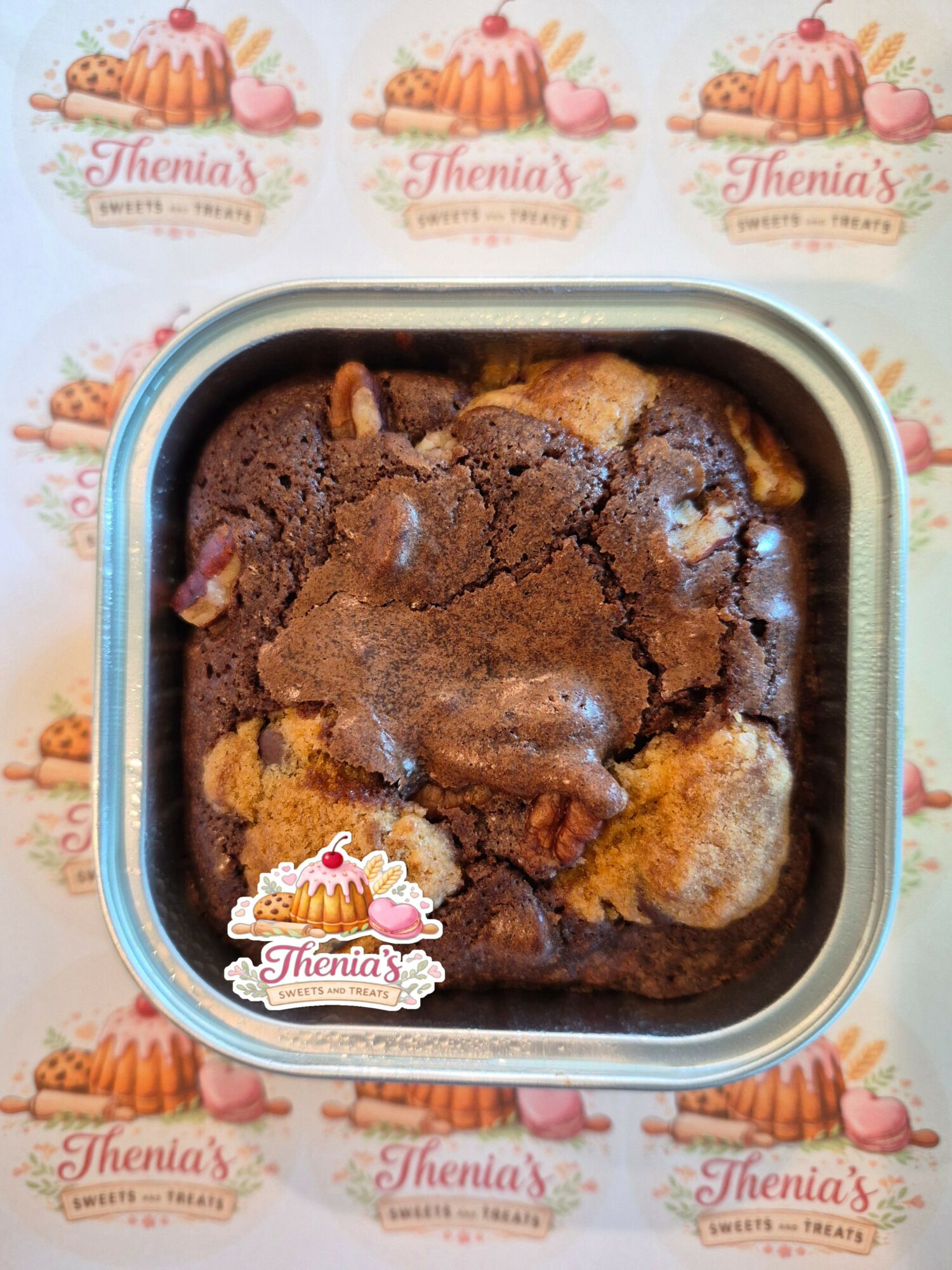 Baked dessert with a cracked top, chocolate and light-colored sections, in a square container, on a cupcake-themed background.