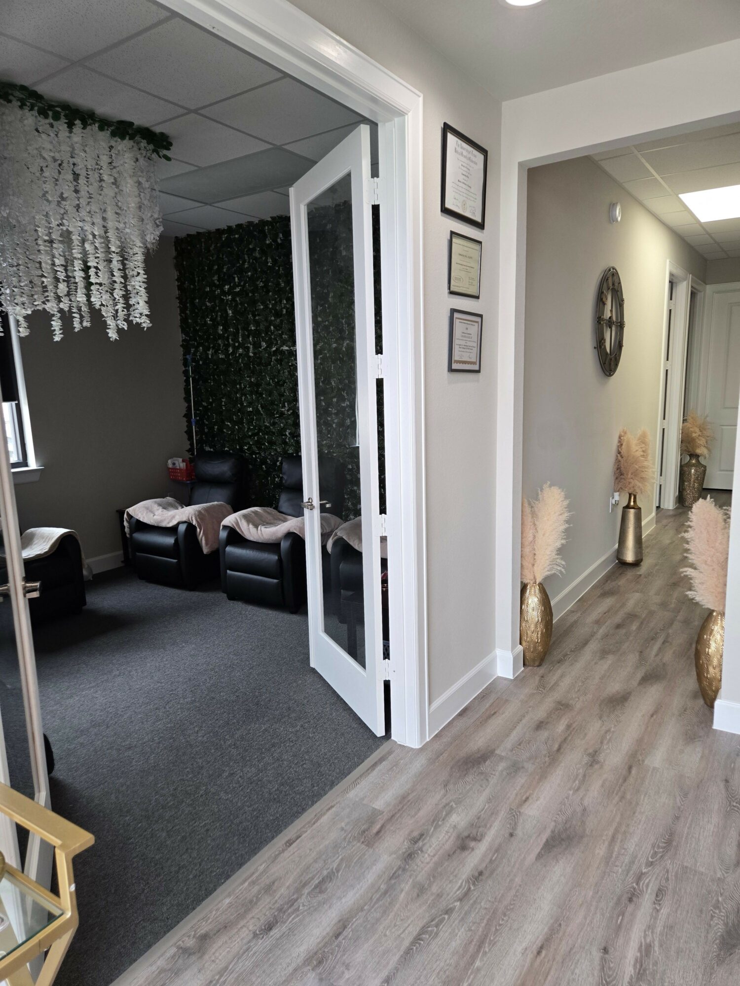 Living room with gray walls, black furniture, and a white door, viewed from the side, with a gray carpet and wooden floor.