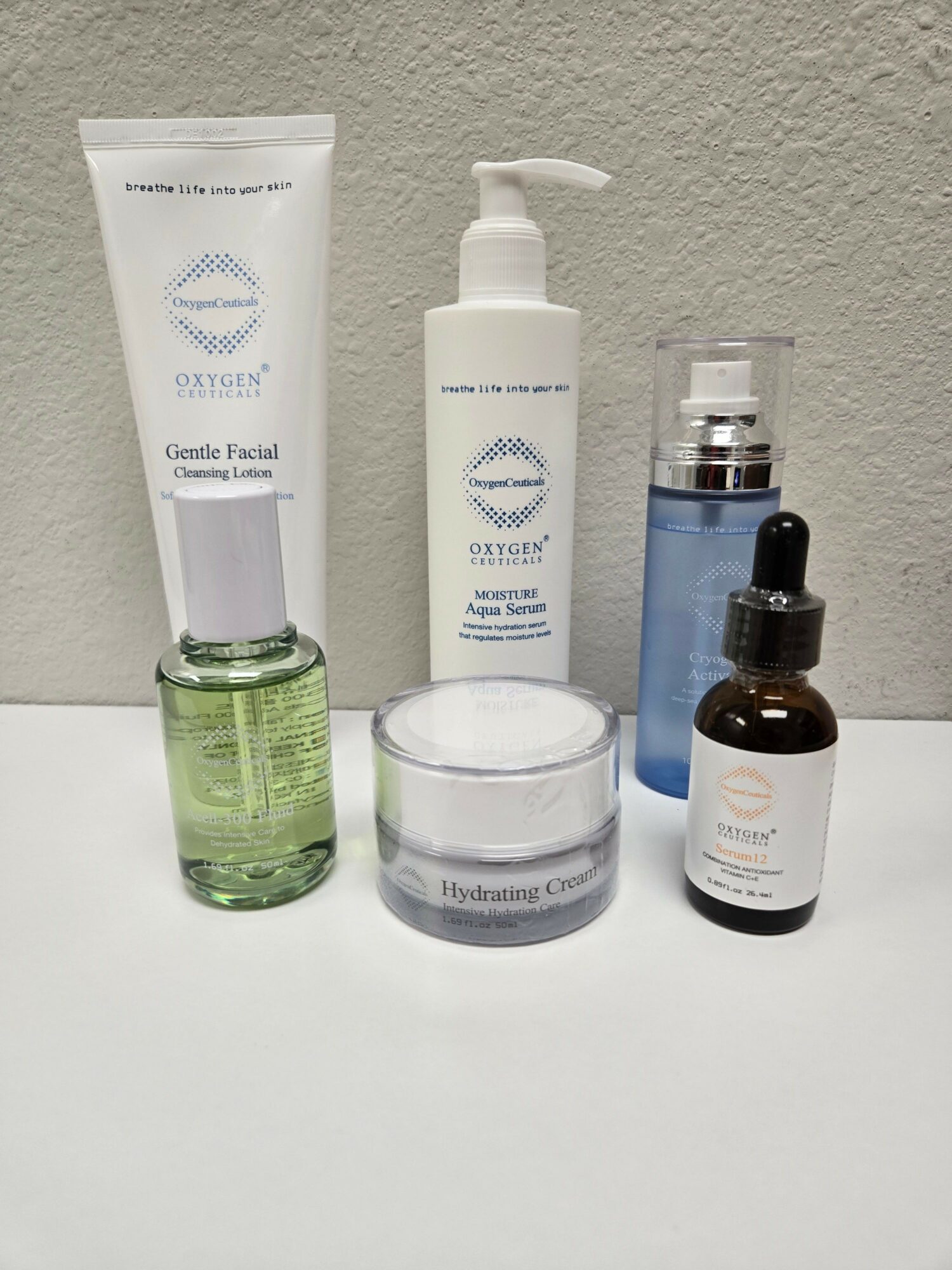 Various skincare bottles and containers on a white surface, including a pump bottle, spray bottle, and jars.
