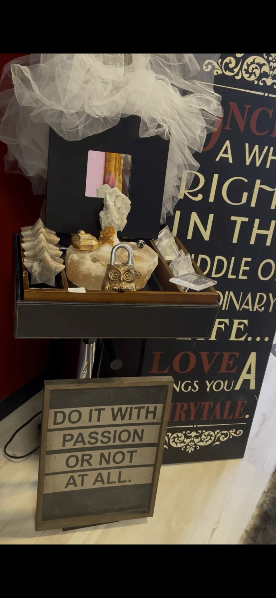 Decorative display with a gift box, gold items, and a sign reading 'Do it with passion or not at all,' in front of a sign with text.