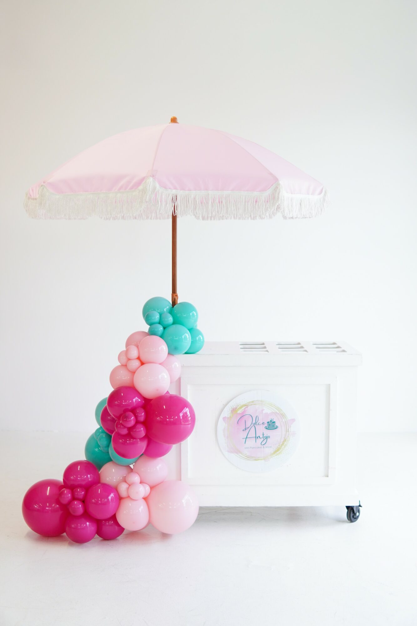 Pink and blue balloon arrangement with a pink umbrella on a white background.