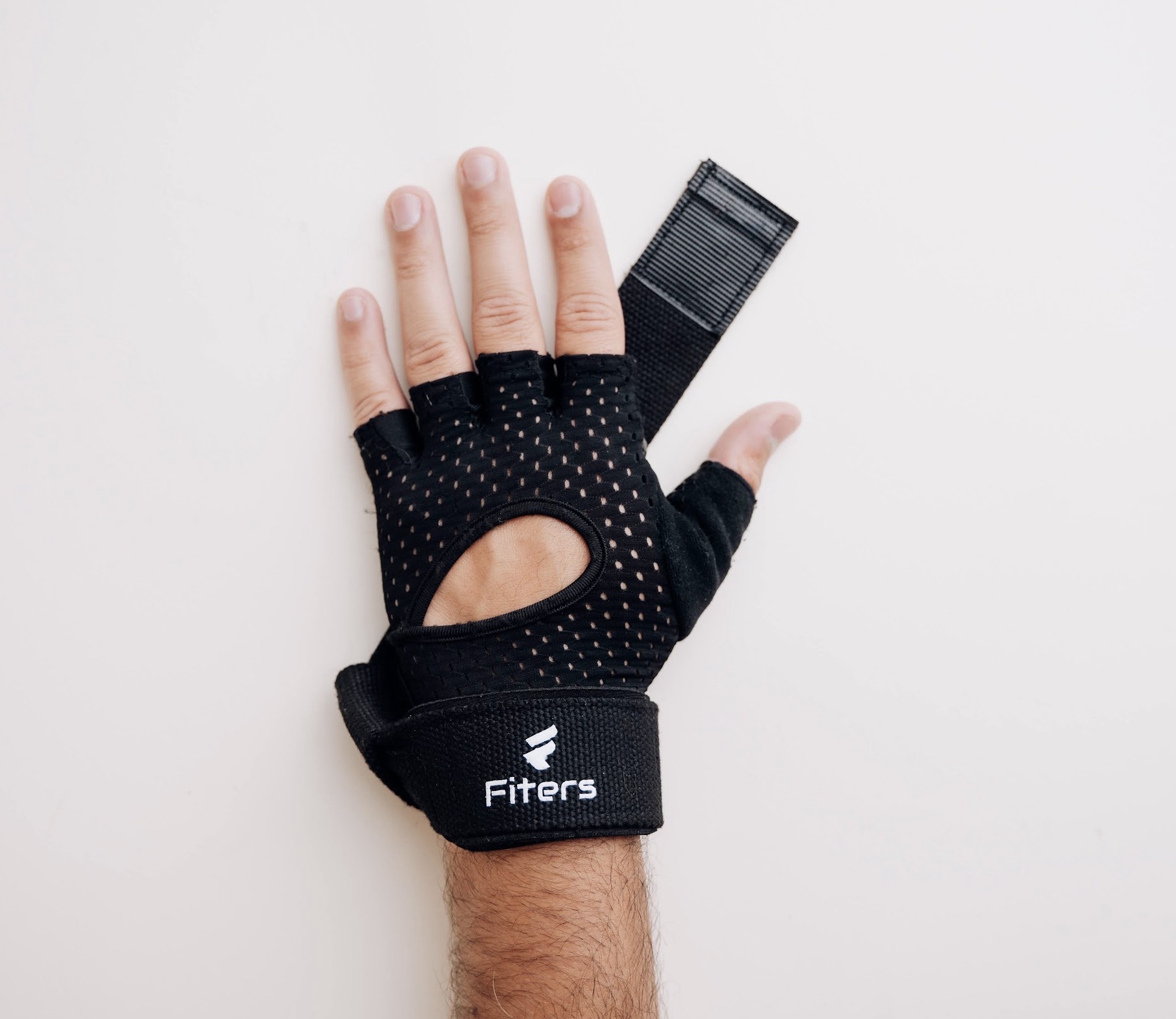 Hand wearing a black fingerless glove with a strap, on a white background.