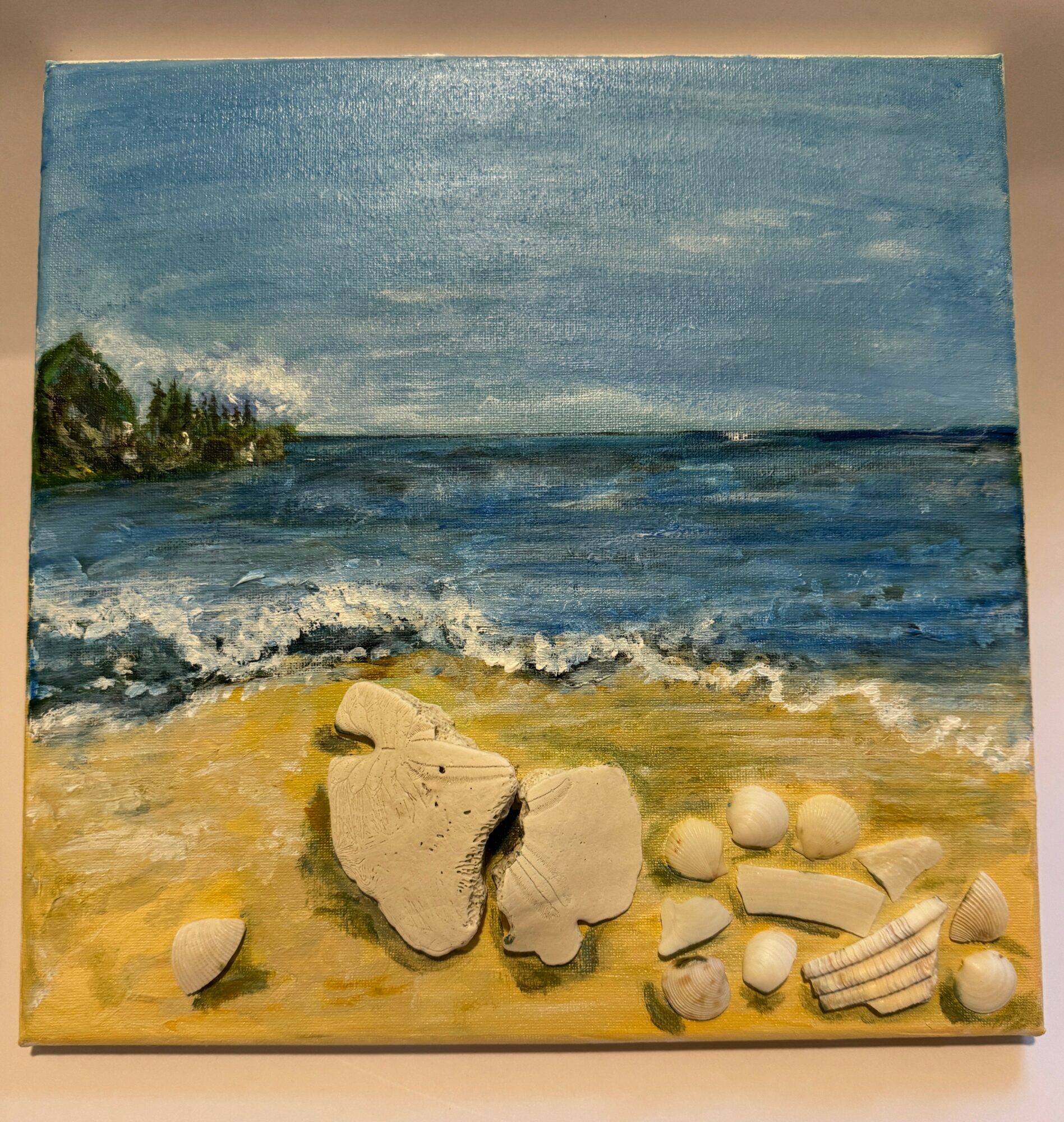 Seascape painting with blue sky, ocean waves, sandy beach, and scattered shells and rocks in foreground.