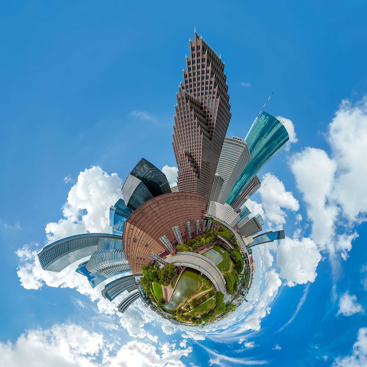 A tiny planet view of a cityscape with tall buildings, green park, and blue sky with clouds.