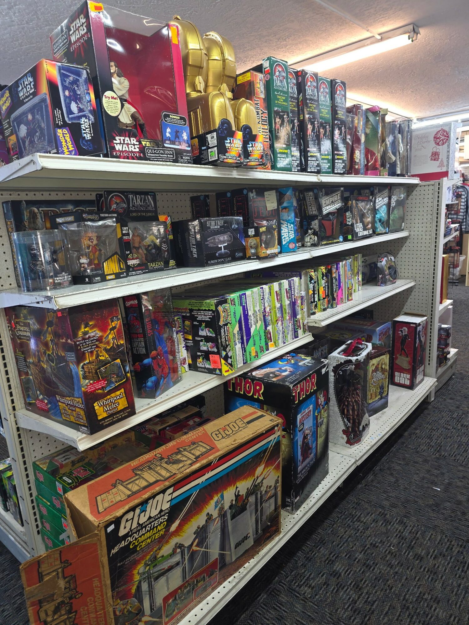 Shelves filled with various toys and action figures, organized on multiple levels in a store aisle.