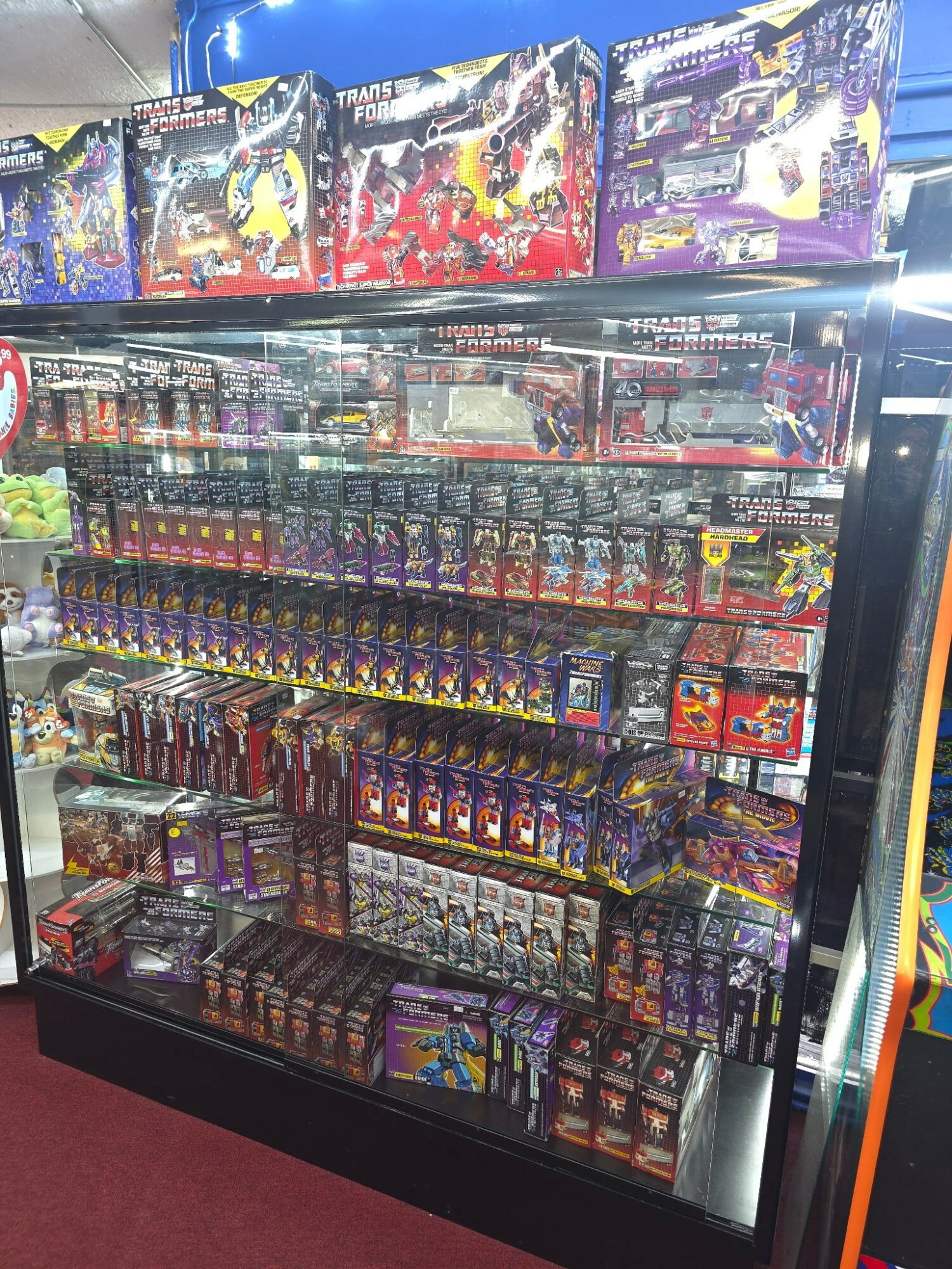 Display case filled with various boxed toys and collectibles, with colorful packaging and multiple shelves, in a store setting.