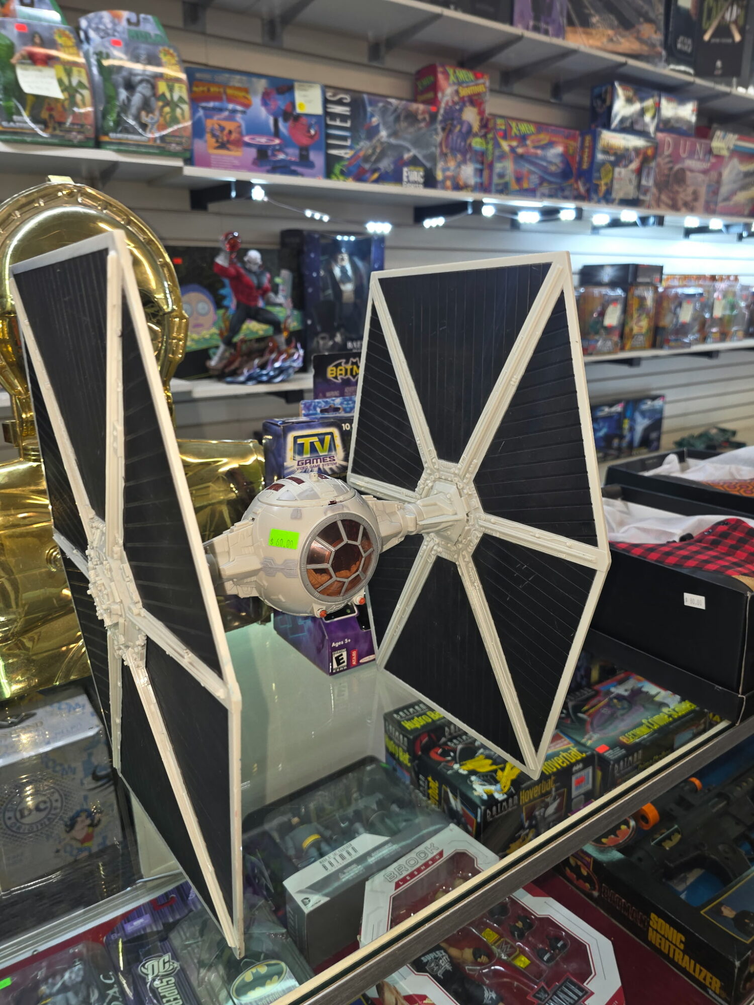 Two Star Wars TIE Fighter model toys displayed on a store shelf, with other toys and boxes in the background.