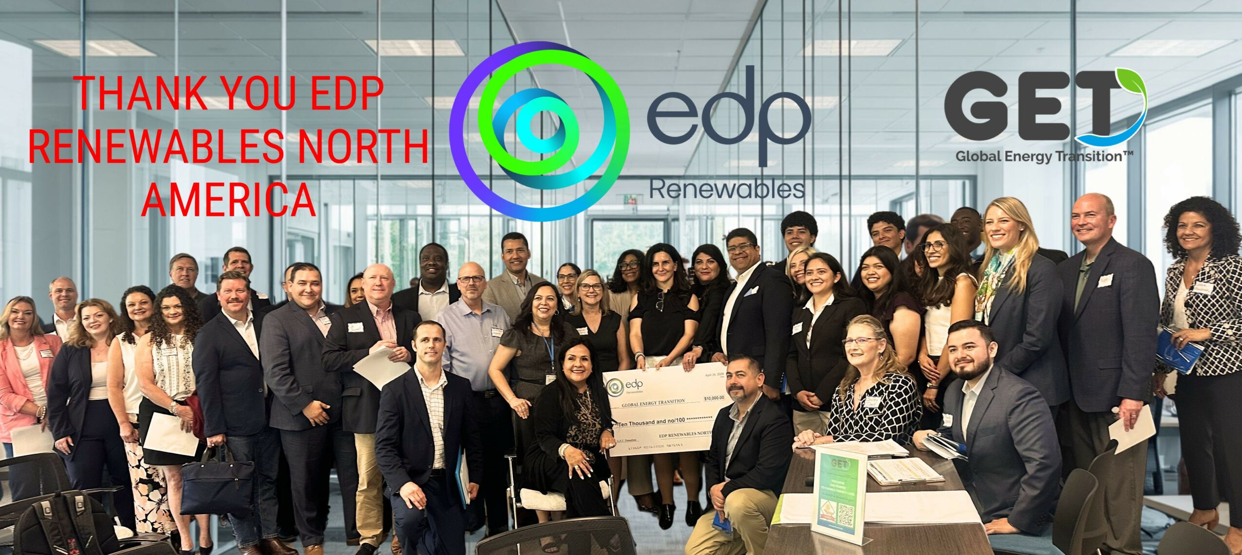 Group of people at an event holding a large check, with logos and banners in the background, celebrating renewable energy achievements.