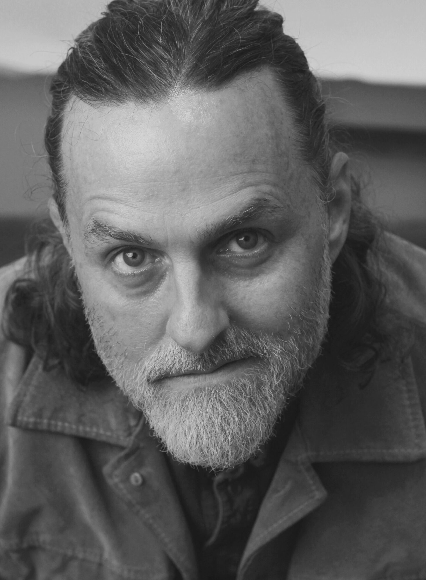 Close-up of a middle-aged man with a beard and mustache, looking directly at the camera, in black and white.