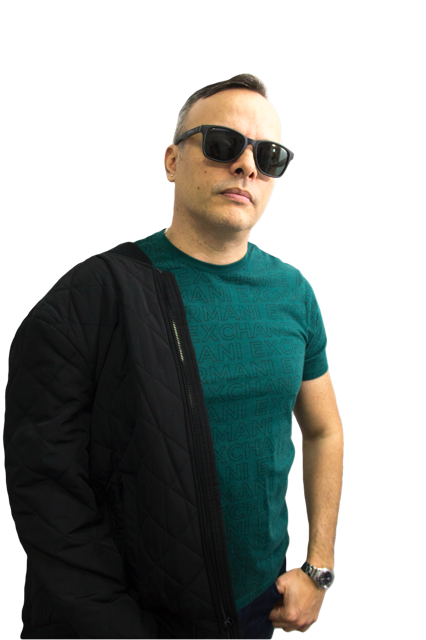 Person wearing sunglasses and a teal shirt, standing with arms at sides, against a black background.