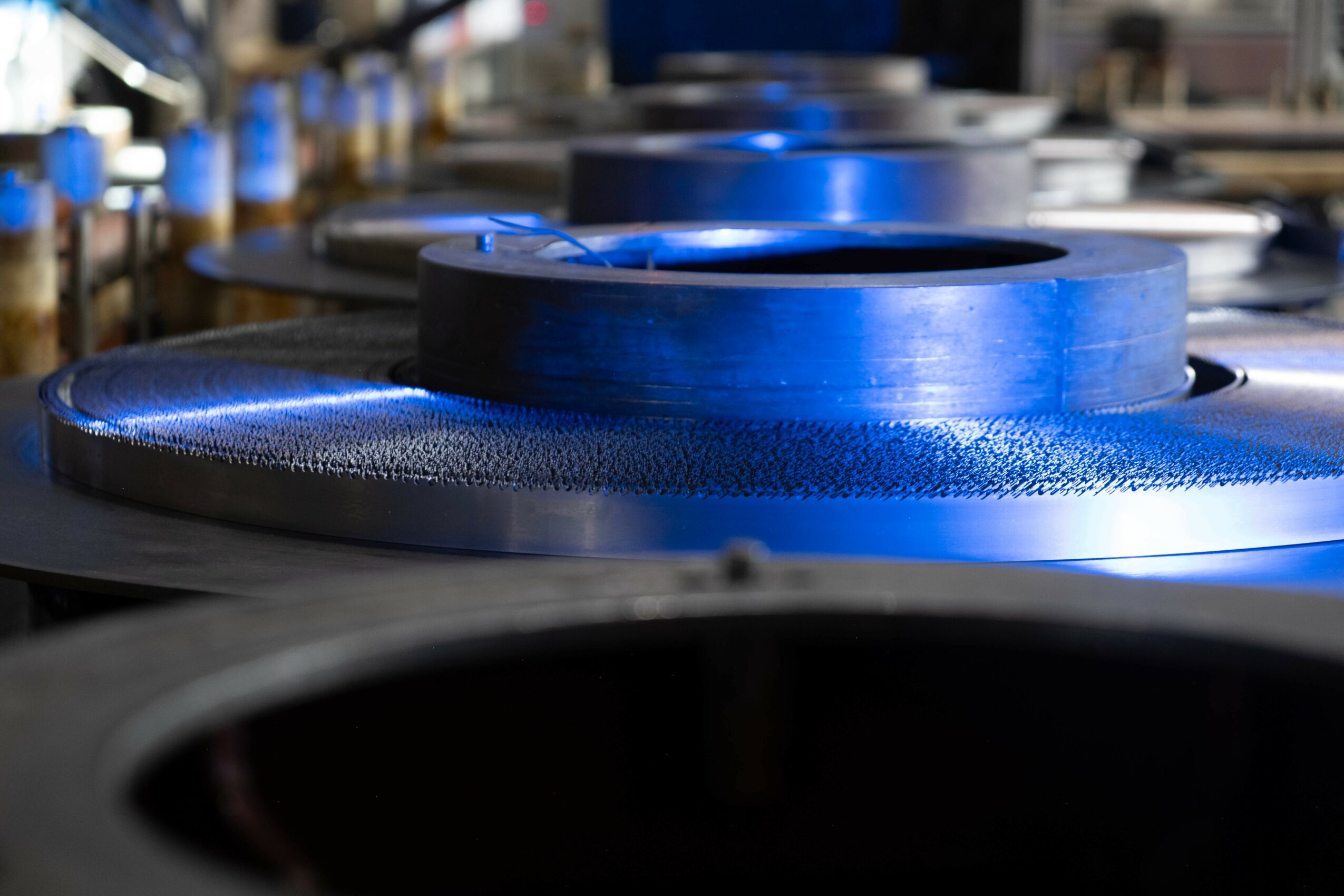 Close-up of blue industrial rollers or wheels in a factory setting, with blurred background.