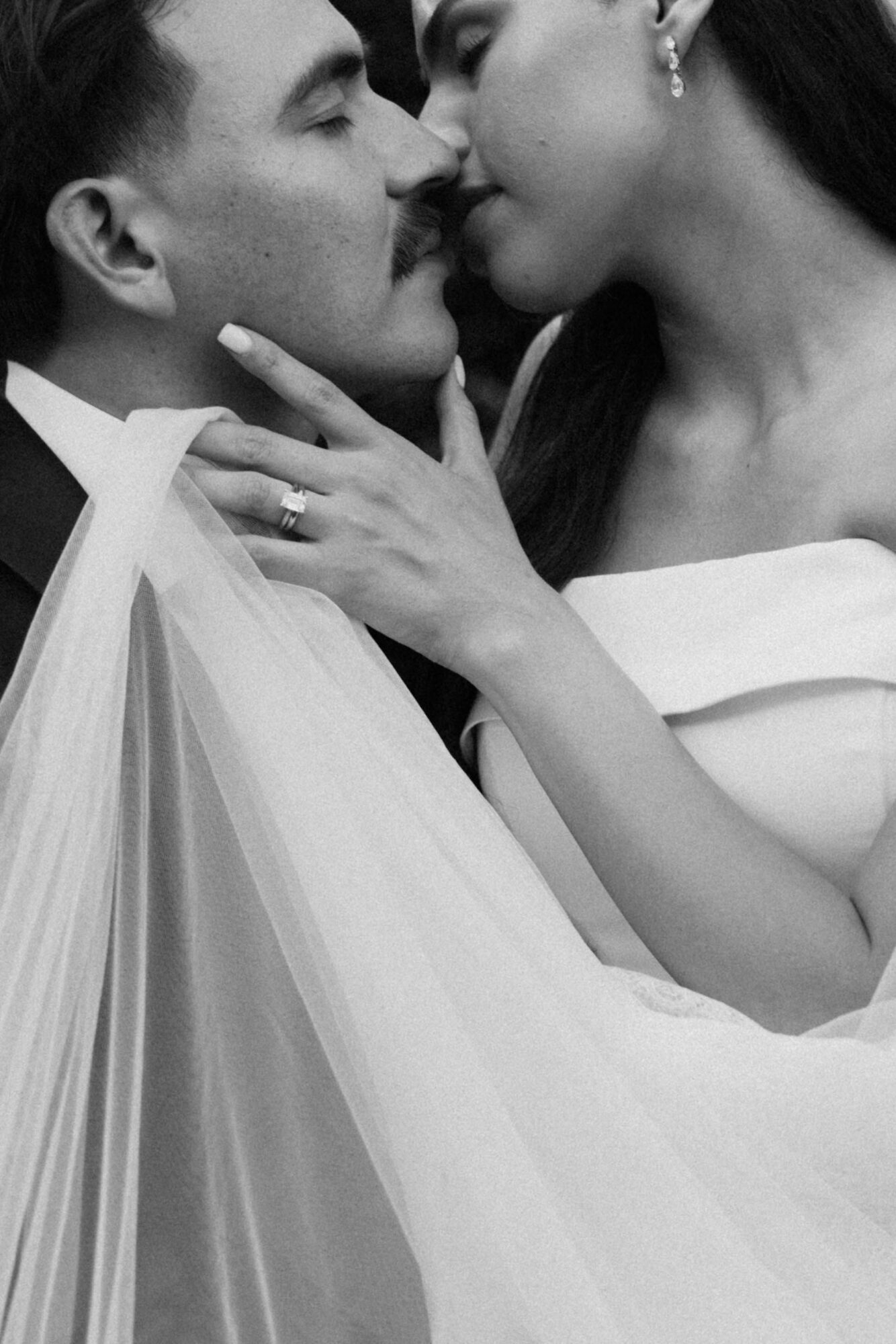 Two people close together, touching faces, with one person's hand on the other's neck, in black and white.