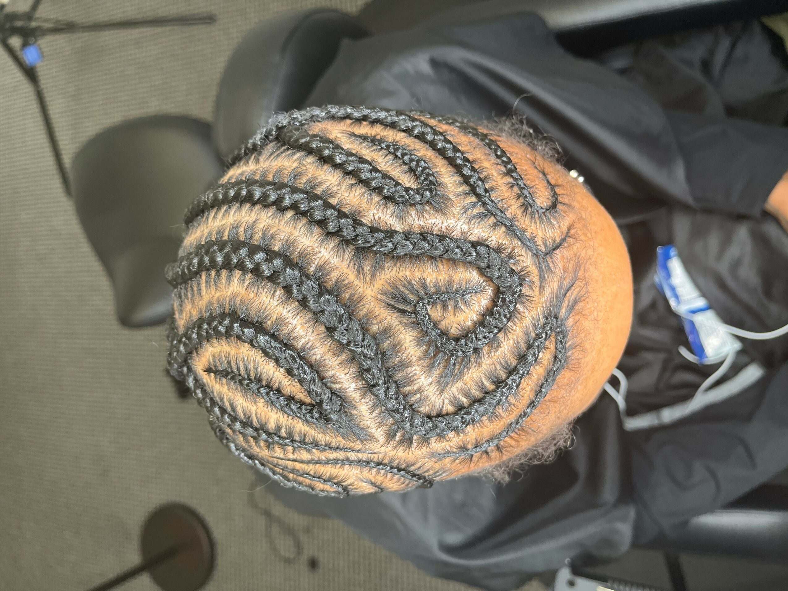 Top view of a person's head with intricate braided hairstyle featuring curved patterns.