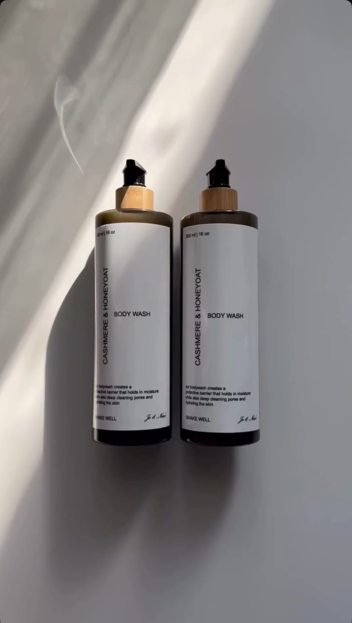Two bottles with dropper caps placed on a surface, with light and shadow in the background.