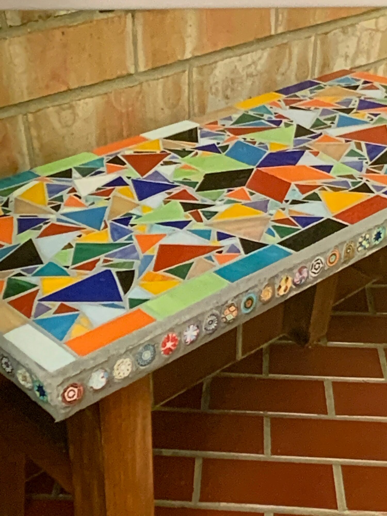 Colorful mosaic tile artwork on a wall with stairs in the background.