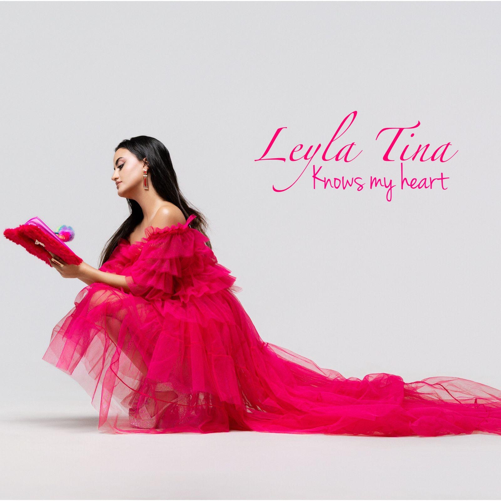 A woman in a pink dress sits on the floor reading a book, with text saying 'Leyla Tina Knows my heart'.