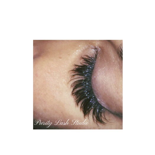 Close-up of a person's closed eye with long, dark, curled eyelashes, and skin visible around the eye.
