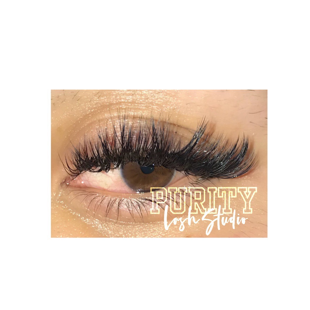 Close-up of a person's eye with long, thick eyelashes and makeup, with text 'Purity Studio' overlayed.