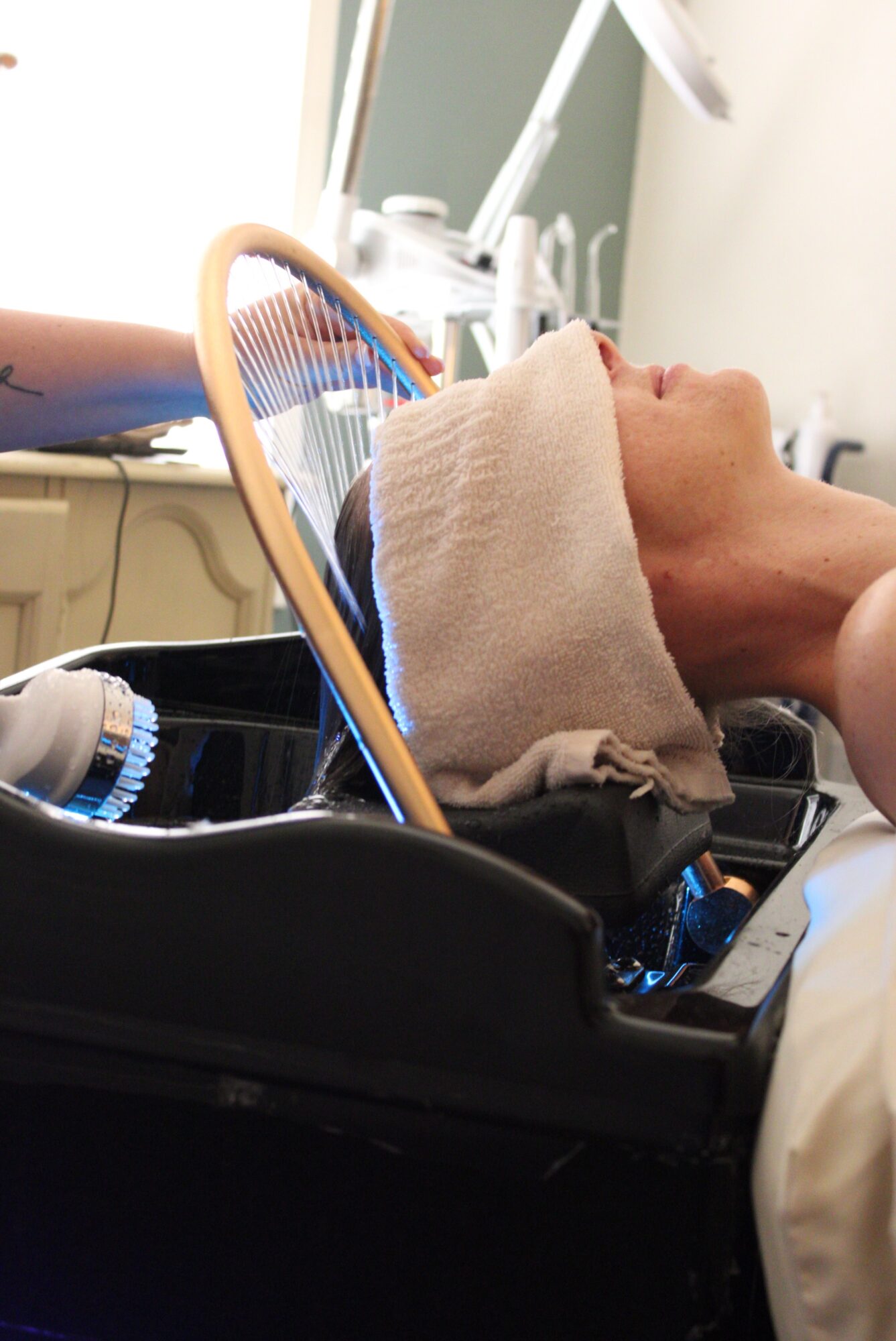 Person lying in a medical chair with a towel over their eyes, in a clinical setting with equipment nearby.