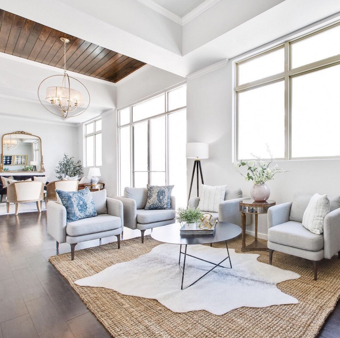 Bright living room with white walls, large windows, and modern furniture including sofas, a coffee table, and a rug.