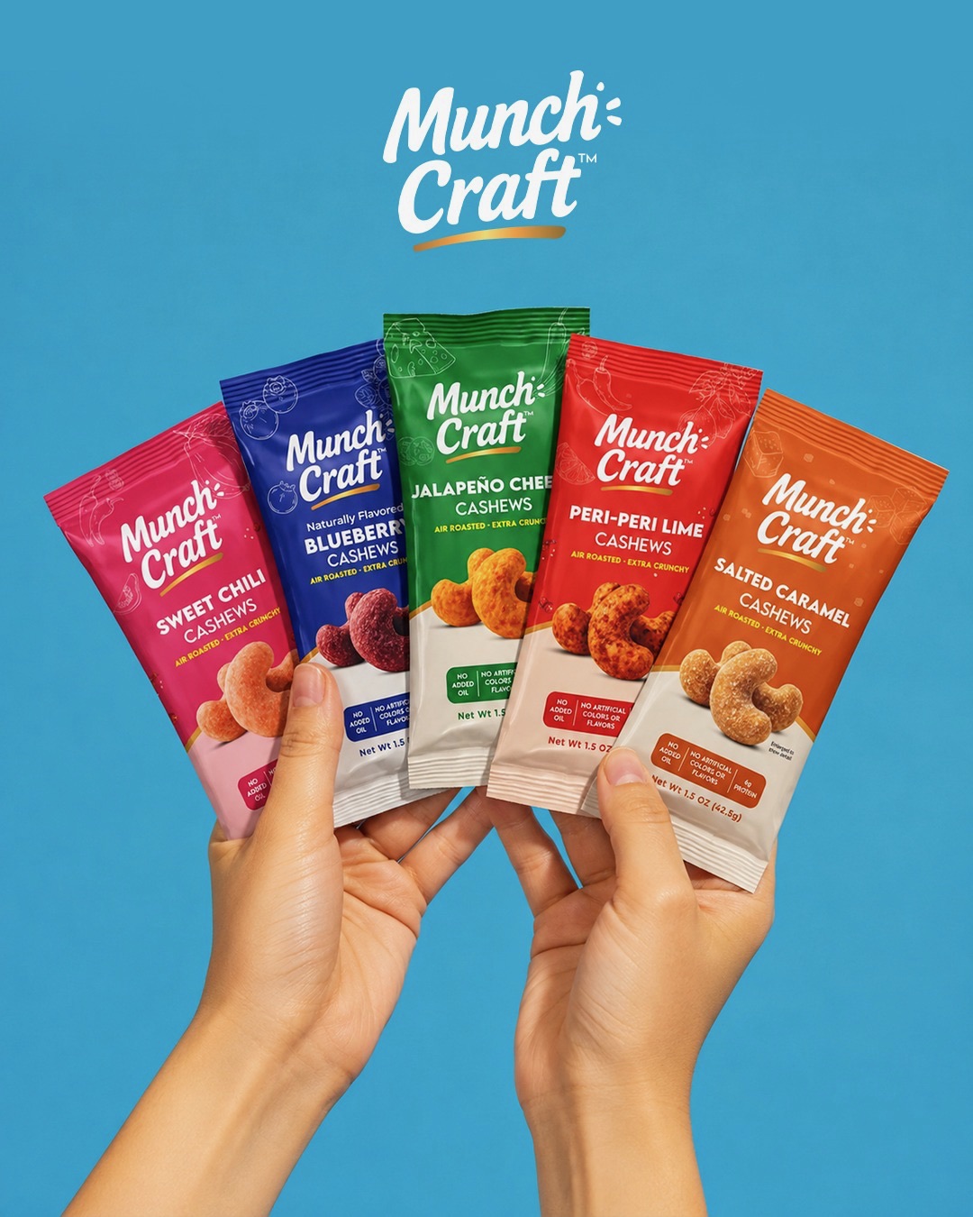 Two hands hold five Munch Craft snack packages against a blue background, with the logo above. The packages are colorful and varied.