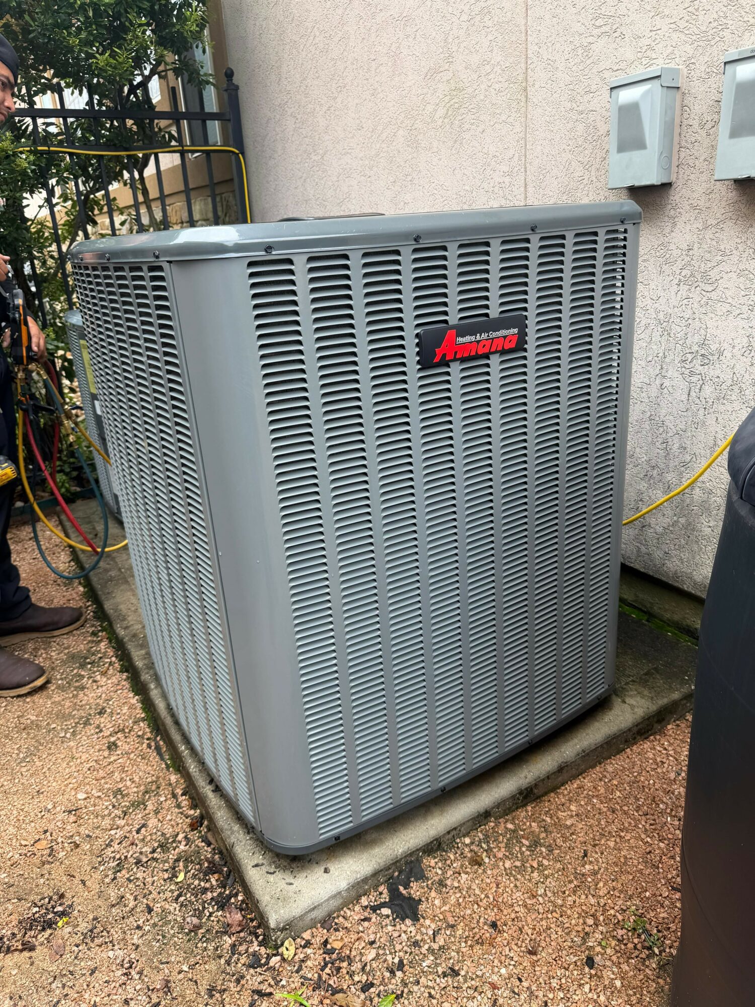 Large gray outdoor air conditioning unit with a red logo, installed on a concrete pad outside a building.