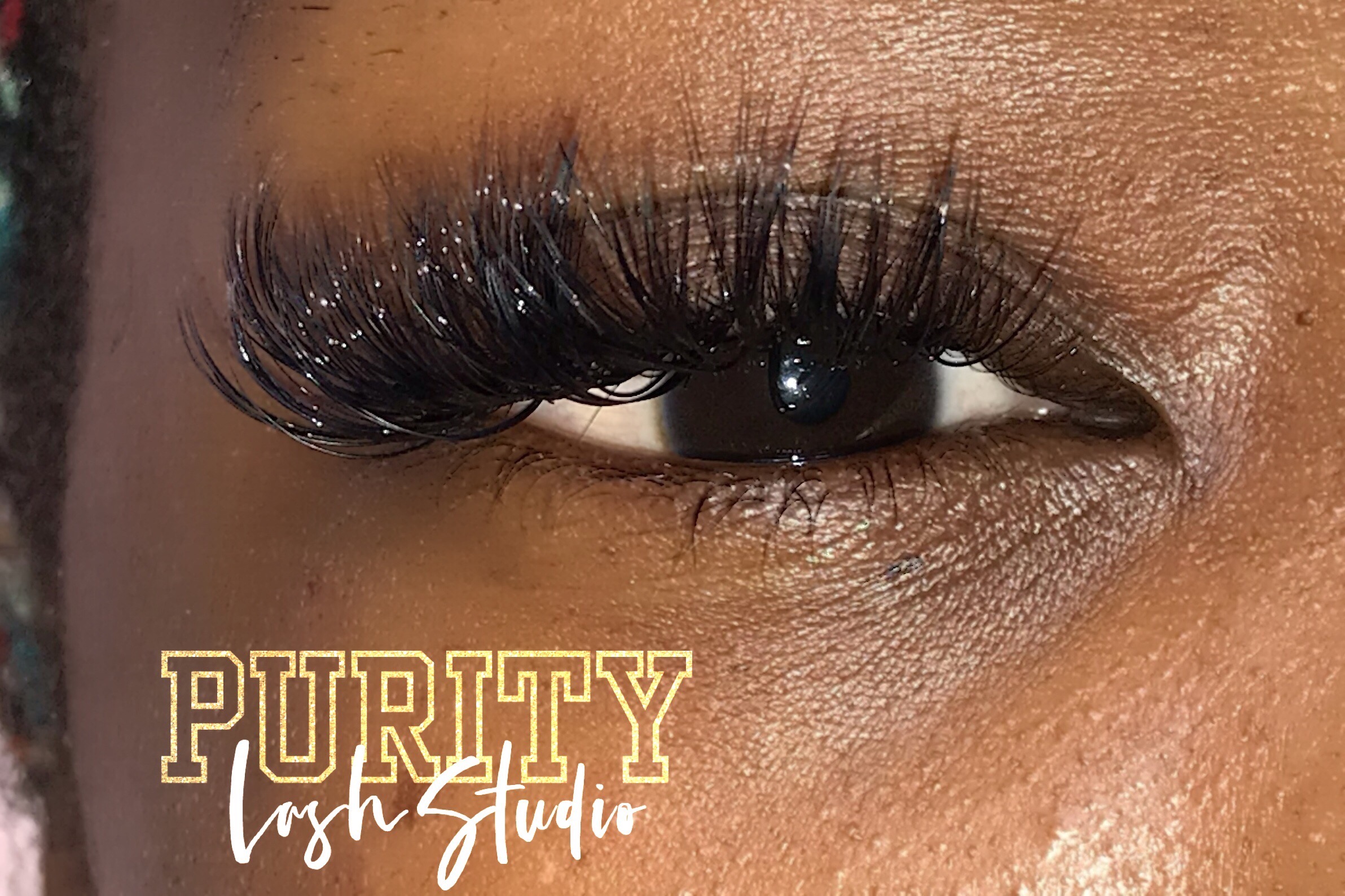 Close-up of a person's eye with long, thick eyelashes and makeup, showing skin texture and eye details.
