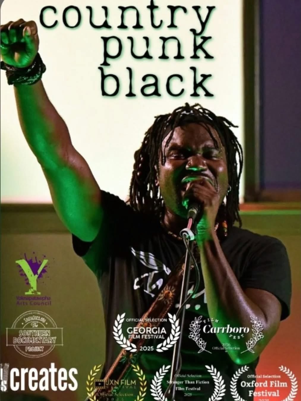 Person with dreadlocks singing into a microphone, raising their arm, with words 'country punk black' in background.