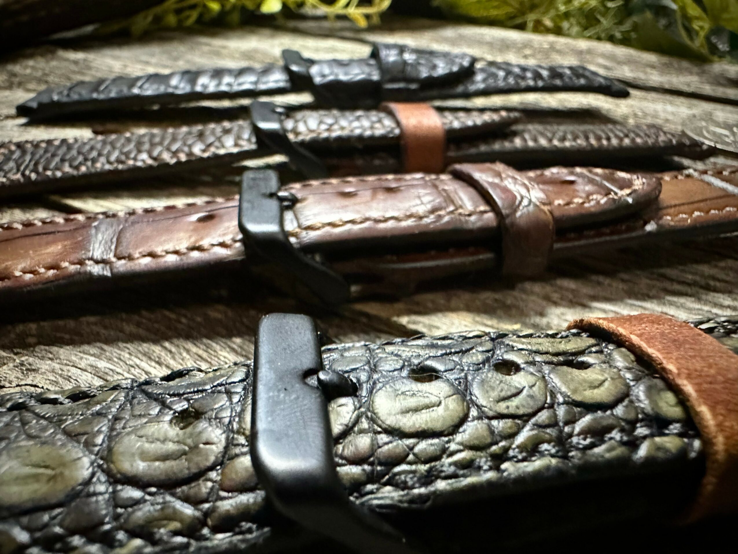 Close-up of three leather watch straps with textured surfaces and metal clasps, arranged horizontally.