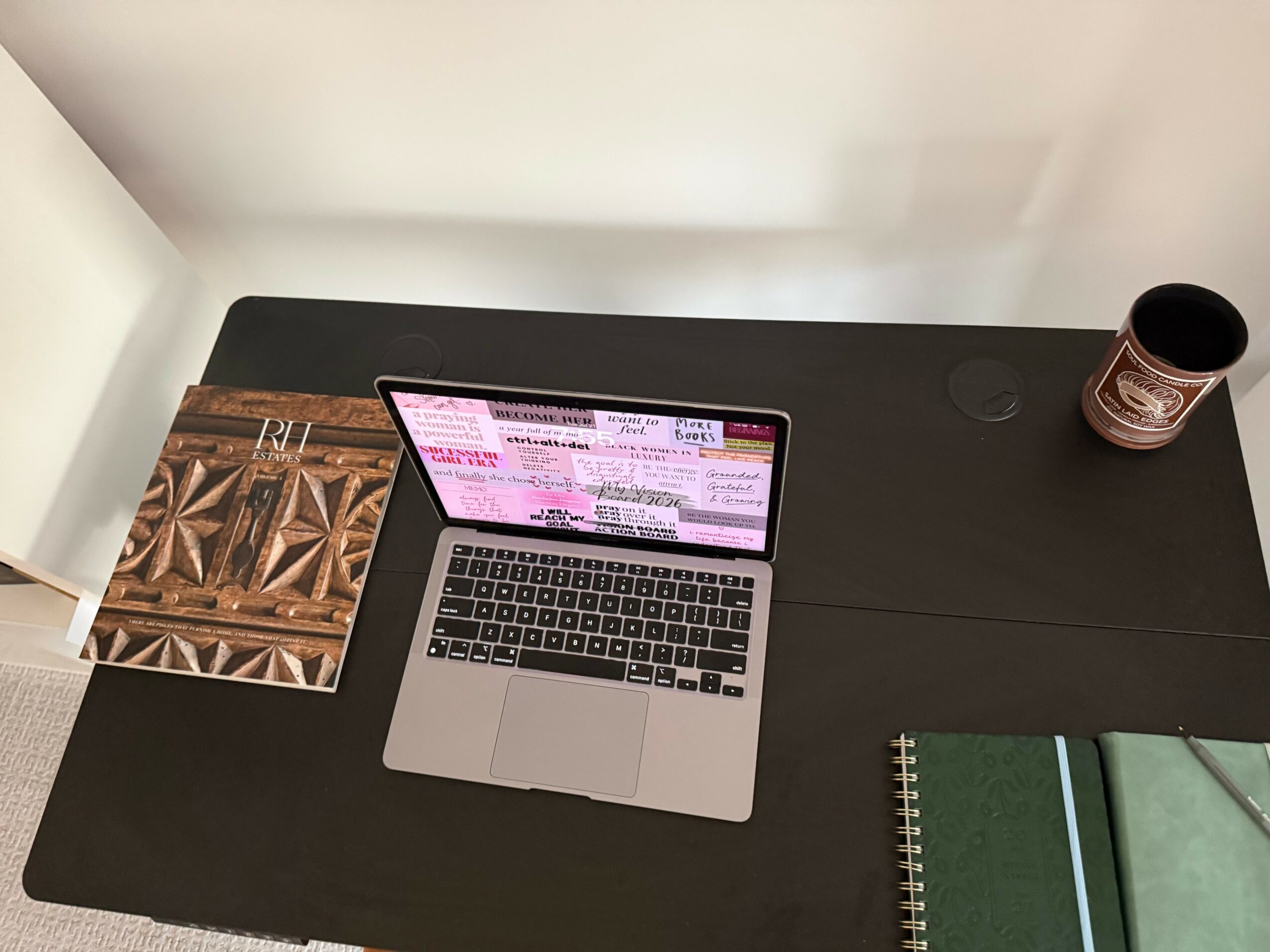 Laptop on desk with notebooks and a cup, viewed from above, rotated 90 degrees clockwise.