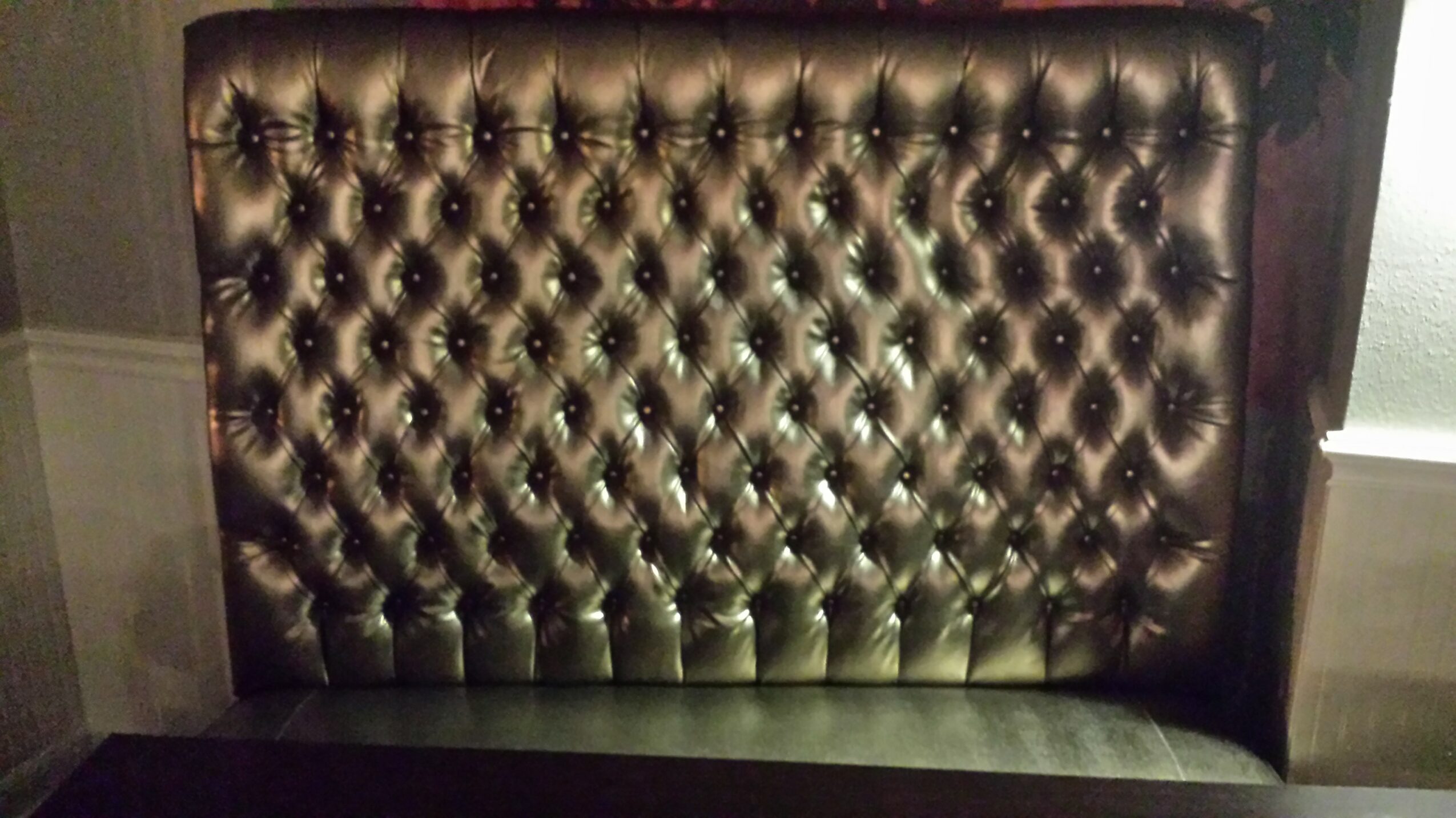 Upholstered headboard with tufted diamond pattern, dark color, and button accents.