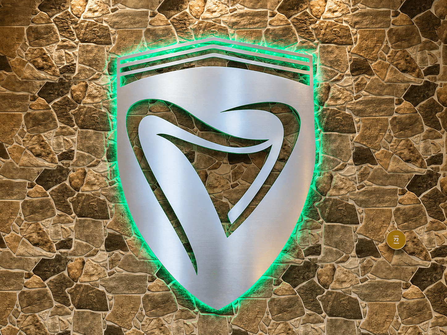 Shield-shaped sign with a stylized snake design, illuminated with green and white lights, mounted on a stone wall.